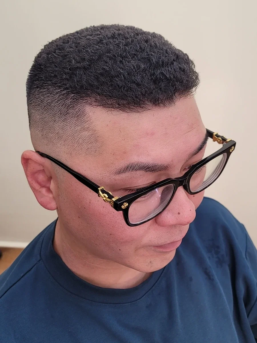 コテ巻きパーマで強い縮れを出し、サイドをフェードで仕上げたスタイル